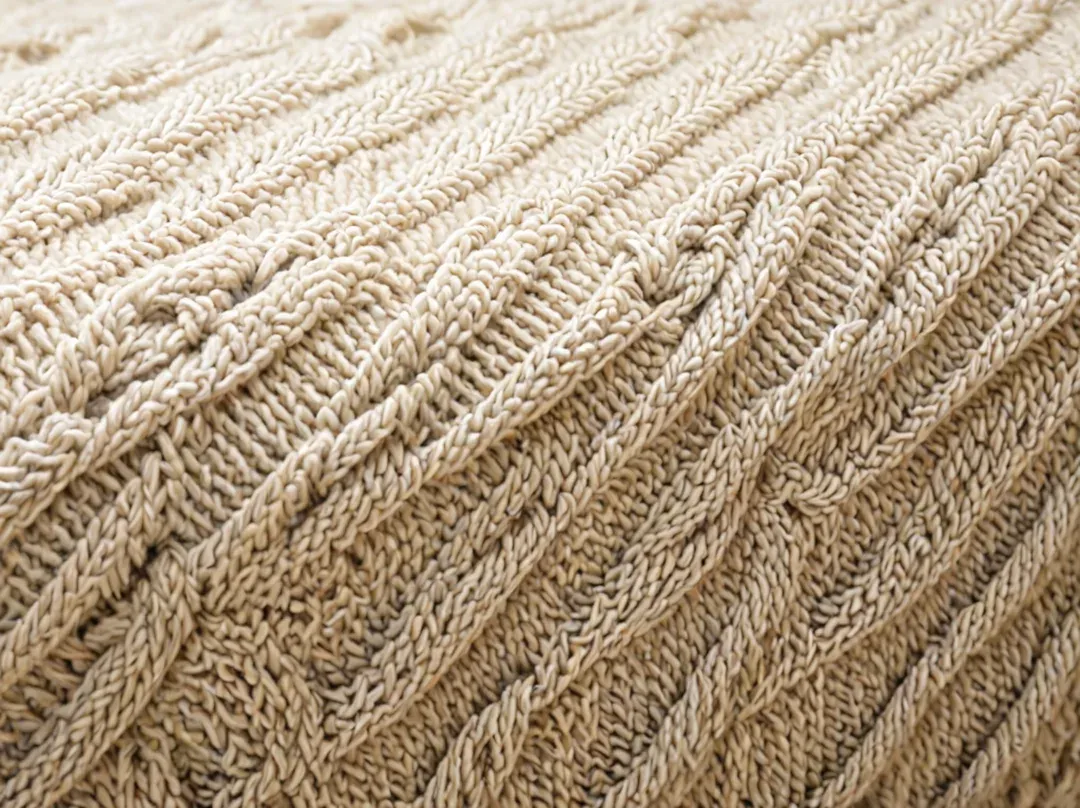 Détail de torsades tricotées sur un pull blanc